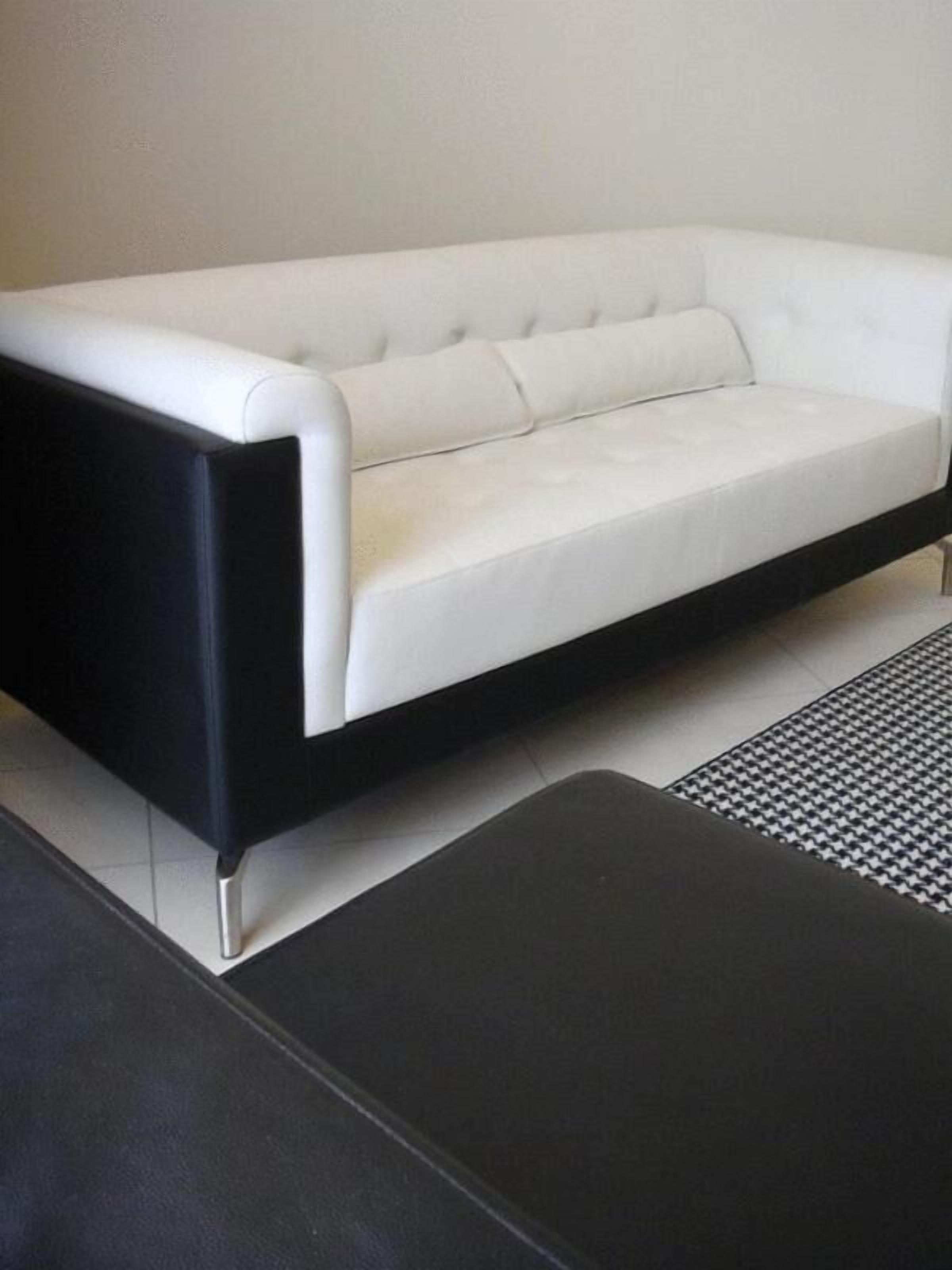 Un sofá blanco con estructura negra en una habitación moderna.