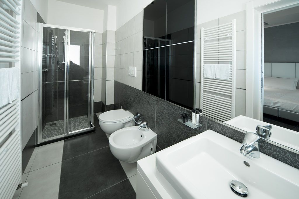 Un bagno moderno con doccia vetro, bidet, lavandino capiente e specchio.