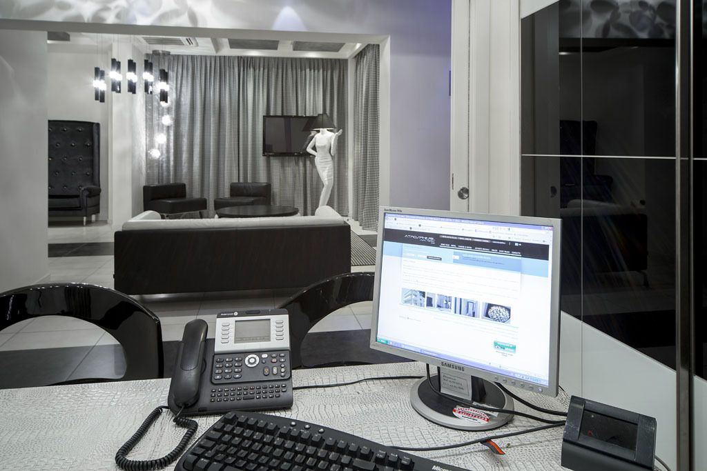 Una habitación de hotel moderna con una cama, un escritorio con una computadora, un teléfono y una televisión.