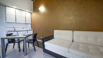 Un espacio habitable compacto con kitchenette, comedor y sofá.
