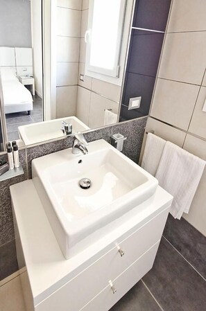 Un baño moderno con un lavabo blanco grande, un espejo y un perchero para toallas.