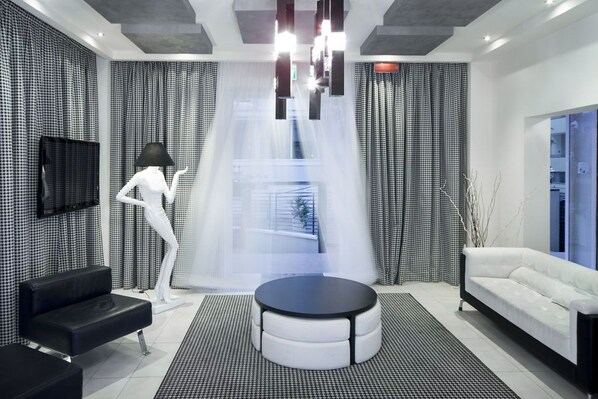 Ein modernes Wohnzimmer mit einer schwarz-weißen Schachbrettwand, einem weißen Sofa, einer schwarzen Lederbank, einem runden schwarzen Tisch und einer weißen Schaufensterpuppe.
