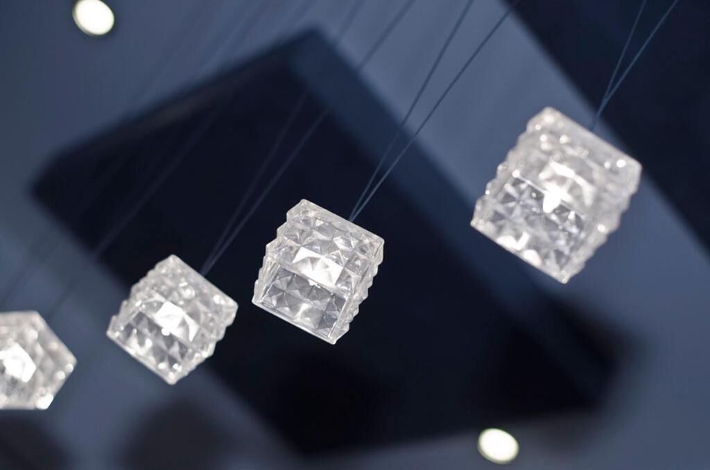 A chandelier with multiple cubic crystal elements suspended by thin wires.