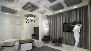 Una sala de estar moderna con un sofá, un reposapiés y un televisor montado en la pared.