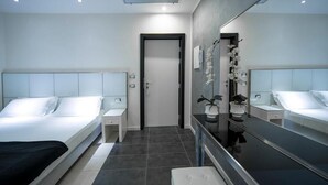 Una habitación de hotel moderna con una cama grande, mesitas de noche, un espejo y un pequeño banco.