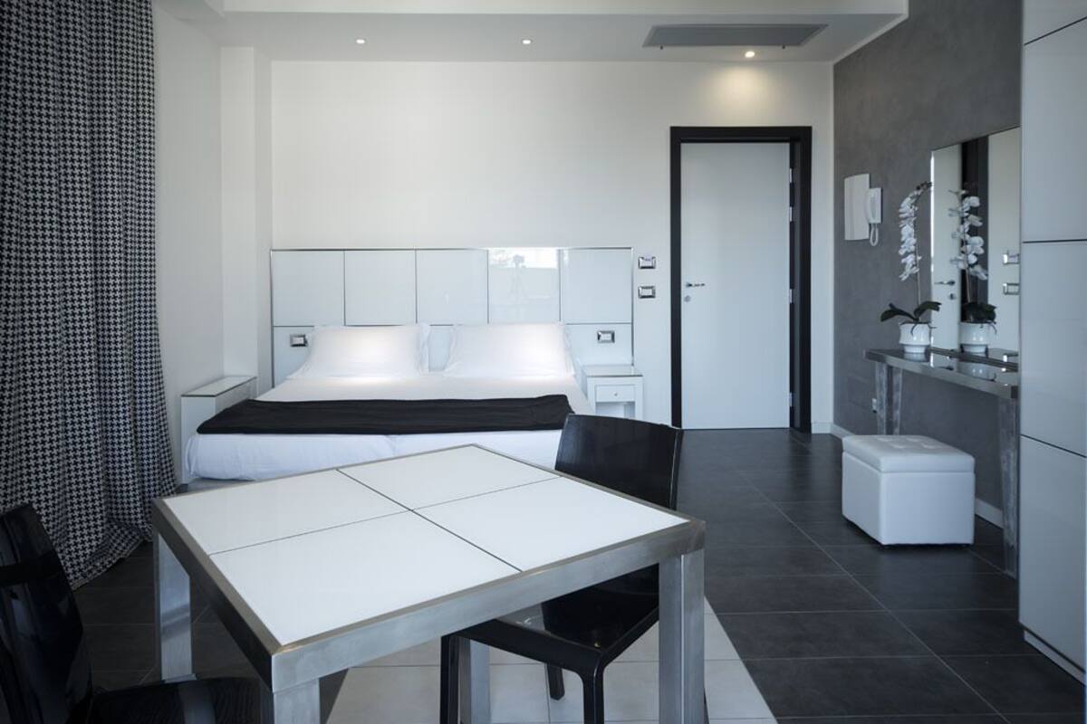 Une chambre d’hôtel moderne avec un grand lit, des tables de chevet, un bureau et une petite kitchenette.