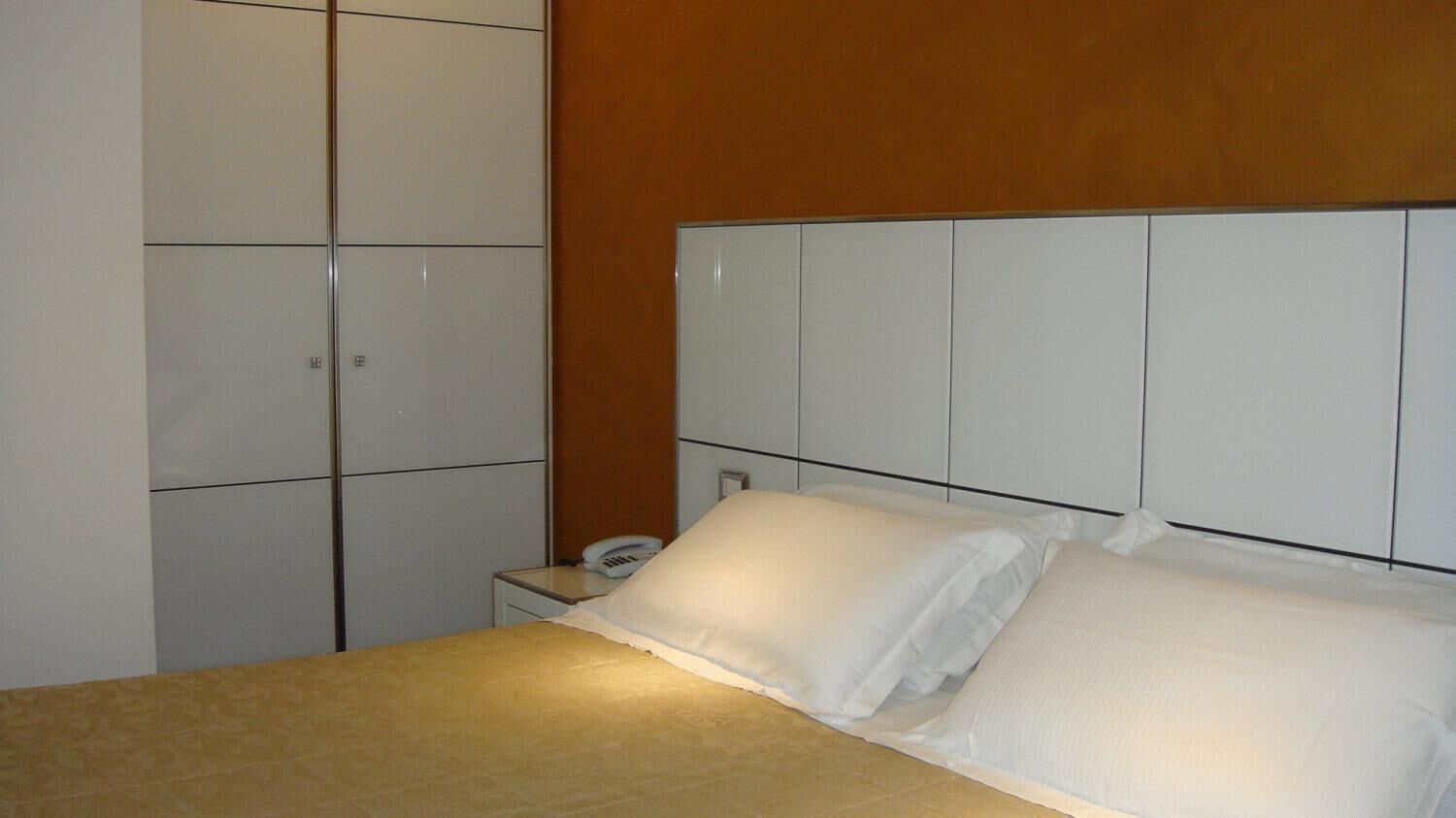 A hotel room with a bed, a nightstand, and a wardrobe.