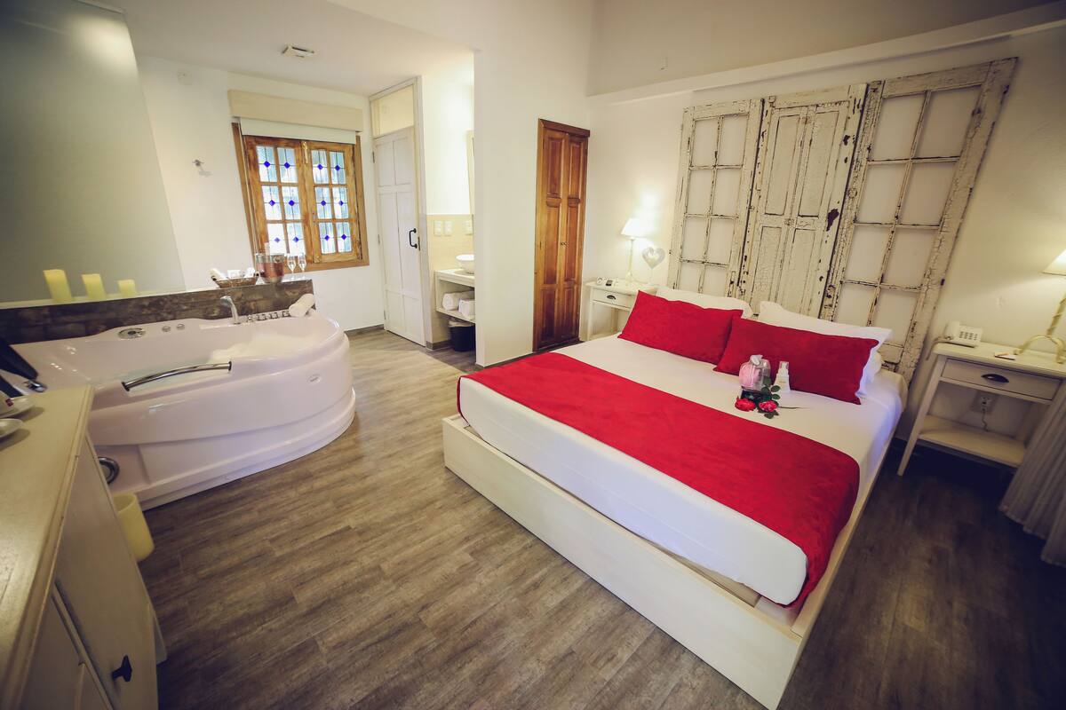Un dormitorio con una cama grande, una bañera, un armario de madera y una ventana con vidrieras.