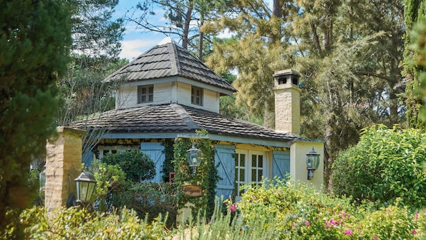 A quaint house with a tiled roof, a chimney, and a garden with various plants and flowers. - Villa Toscana Boutique Hotel - Adults only (Punta Ballena)