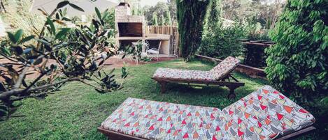 Un patio trasero con dos sillones, una zona de barbacoa y una terraza de madera.