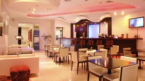 Un hall de hotel con mostrador de recepción, zona de estar y bar.
