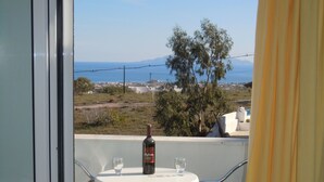 Varanda com mesa e duas cadeiras, uma garrafa de vinho e dois copos.