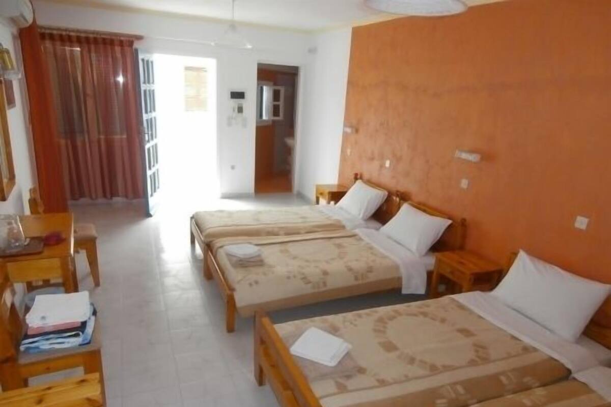 Habitación de hotel con dos camas, un escritorio de madera y una silla.