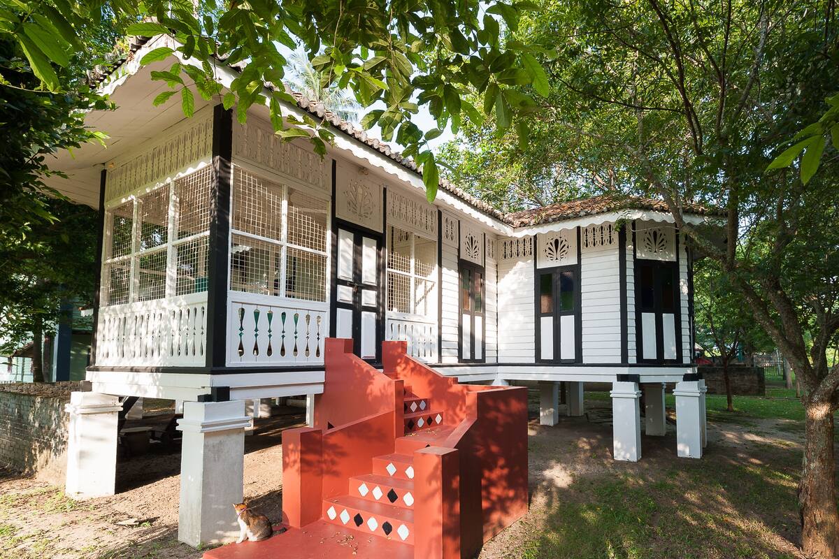 A traditional building with multiple rooms, a red staircase, and a garden area.