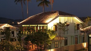 A two-story building with a tiled roof, surrounded by palm trees and a well-maintained garden. - Temple Tree at Bon Ton (Langkawi)