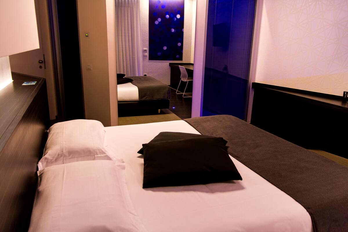 A hotel room with a bed, a desk, and a chair.