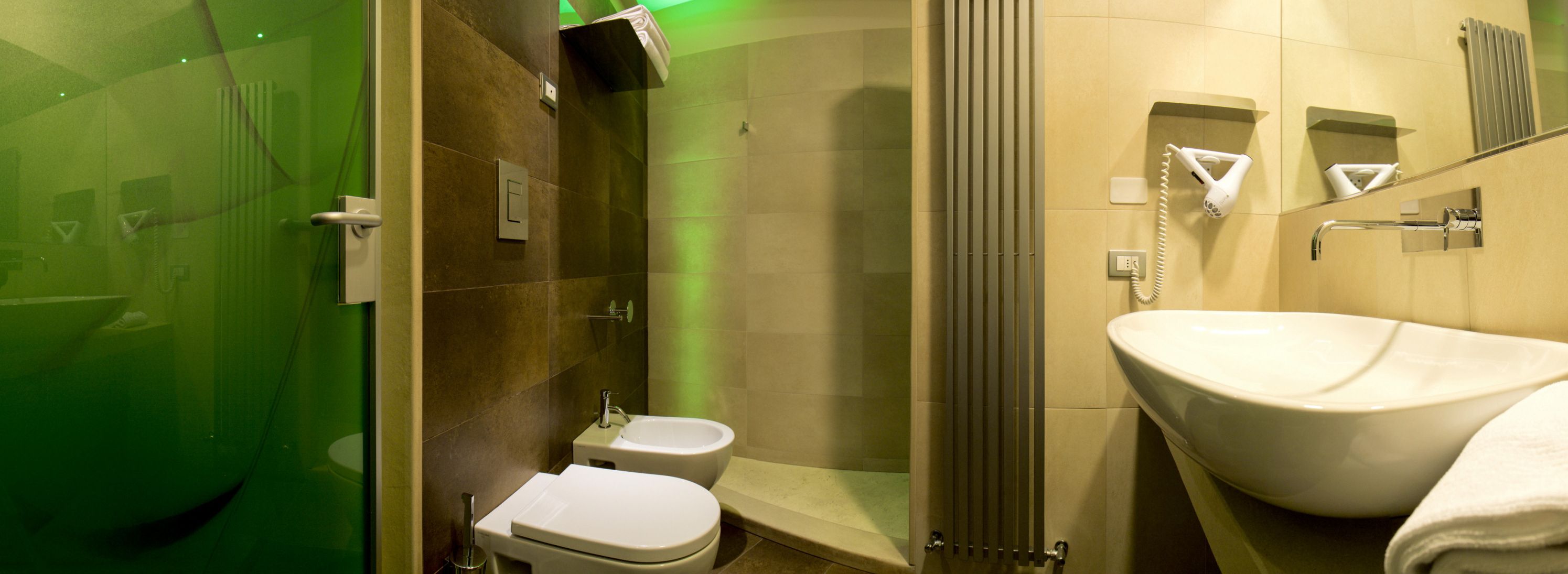 Un bany modern amb plat de dutxa de vidre, vàter i un gran lavabo.