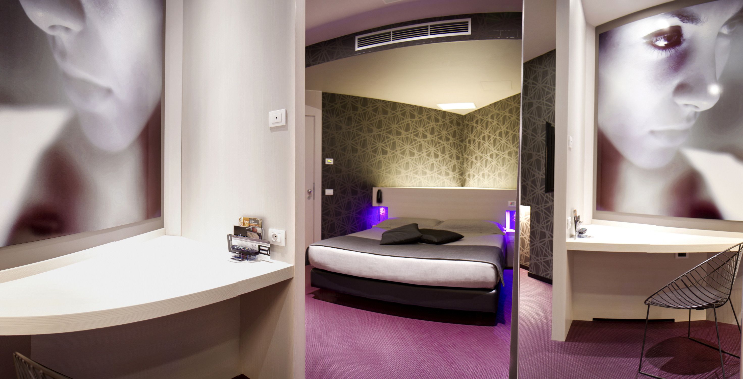 A modern hotel room with a curved bed, a desk, and a chair.