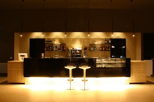 Una zona de bar con mostrador, taburetes y una pared de azulejos.
