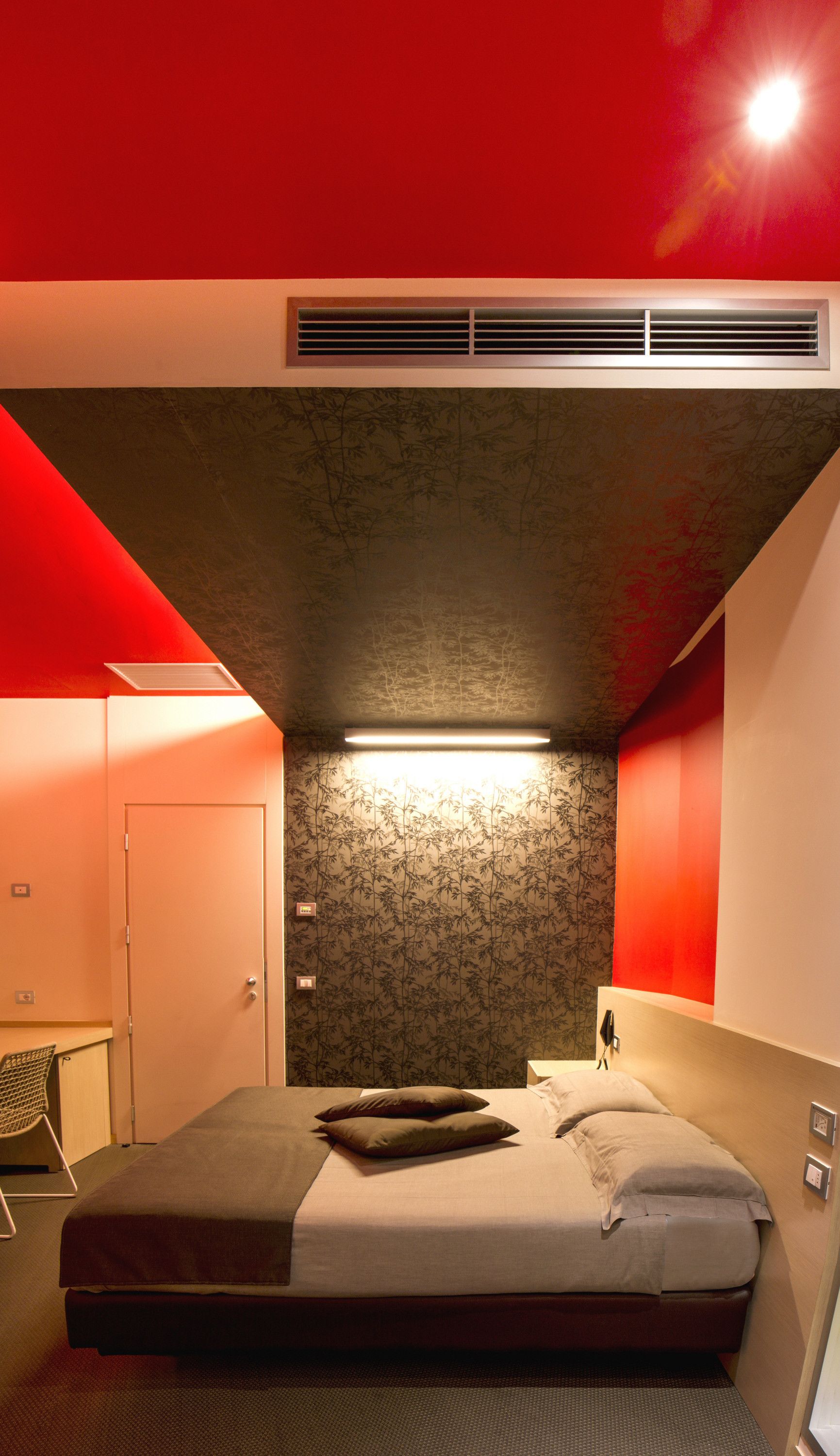 A compact bedroom with a bed, bedside table, and a wall-mounted heater.