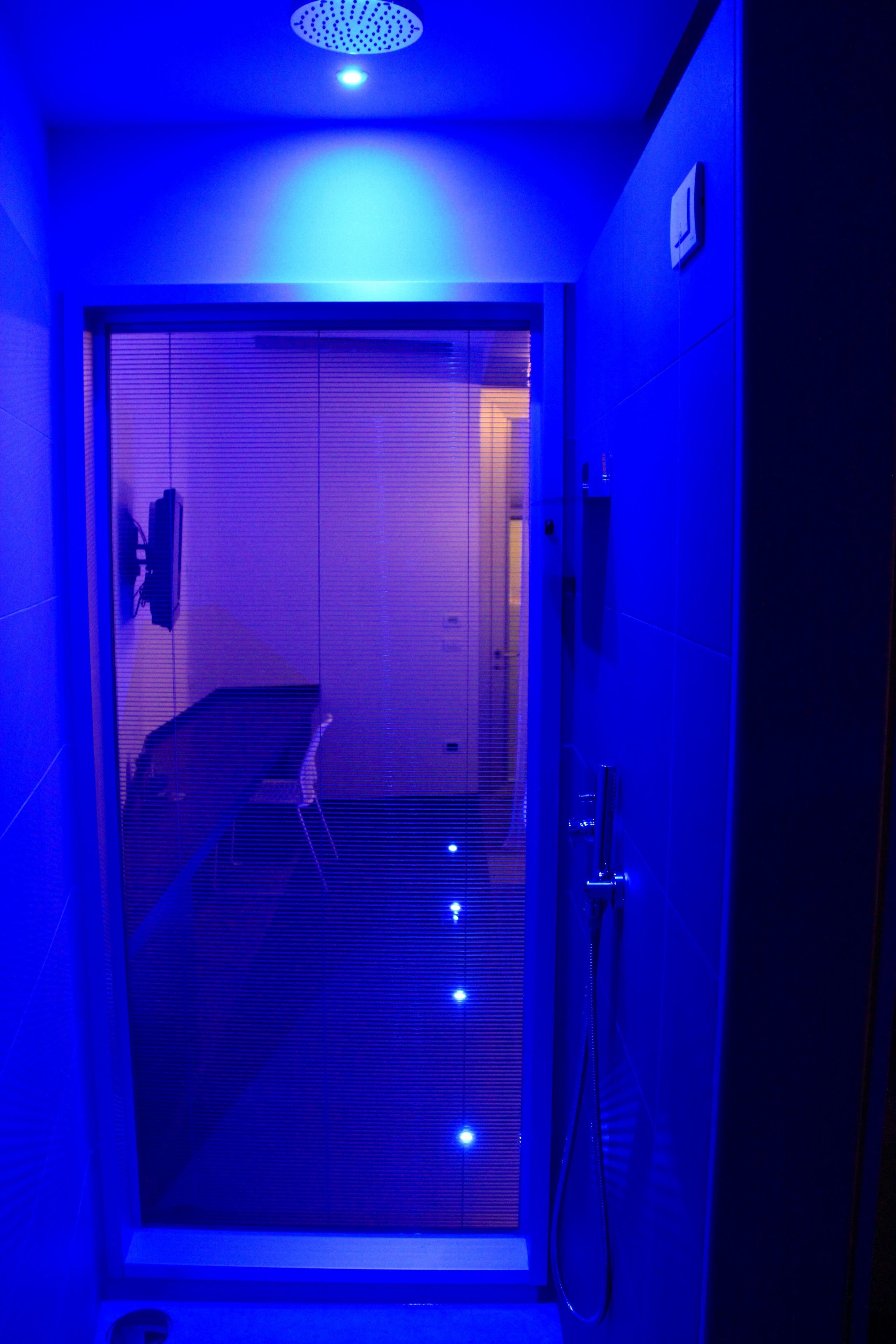 A room with a glass door leading to a staircase, a shower area, and a ceiling light fixture.