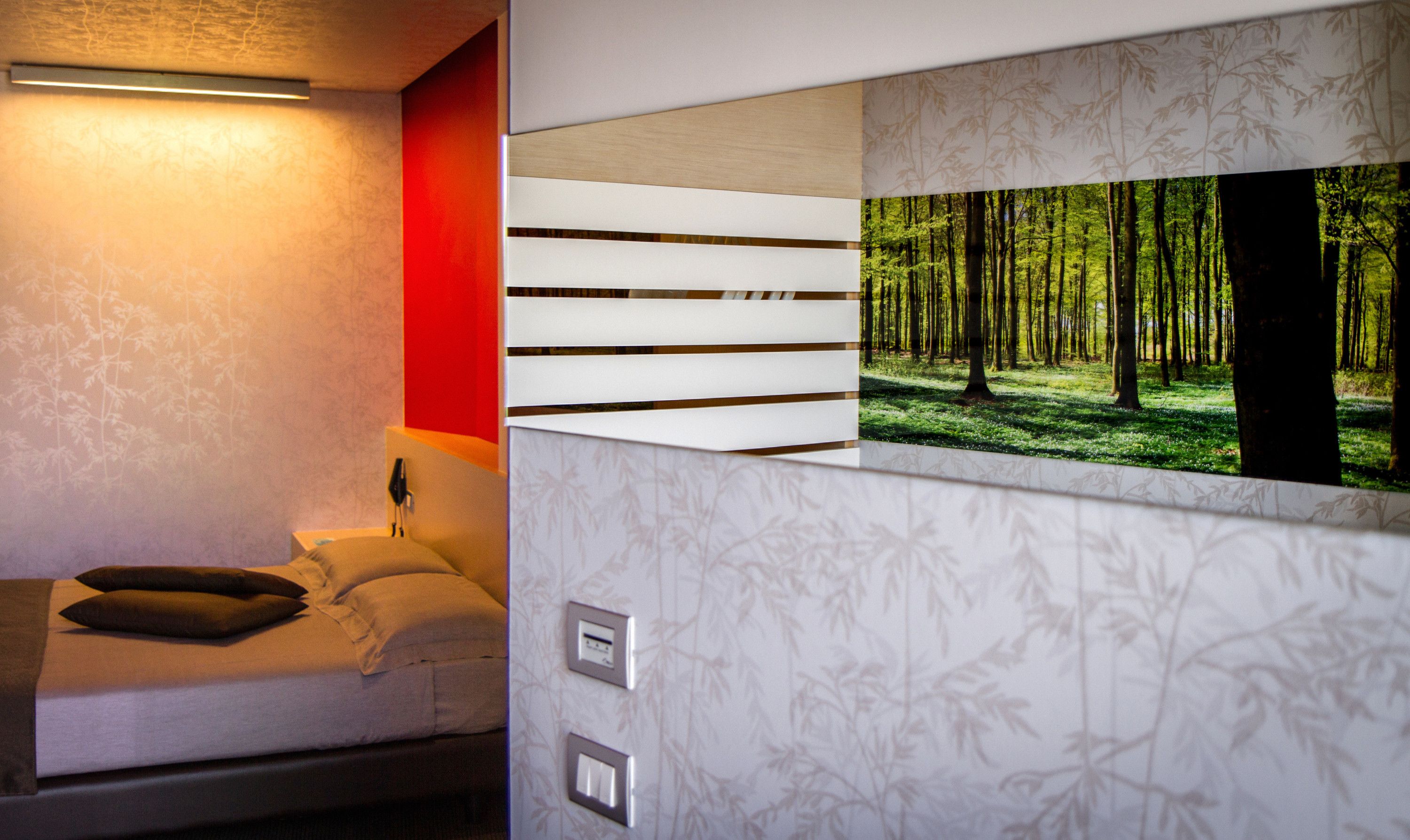 A modern room with a bed, a wall-mounted TV, and a thermostat.