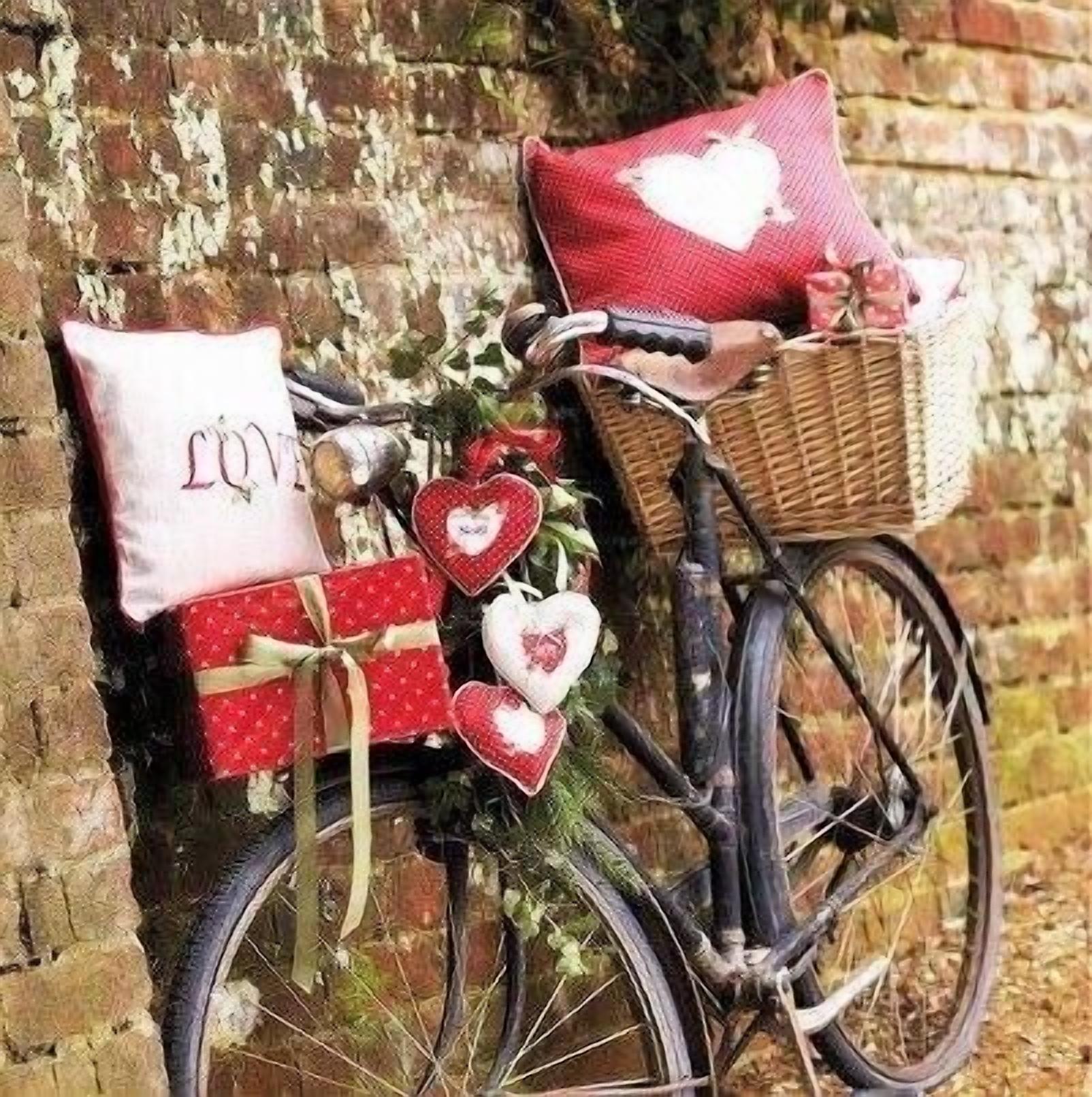 Un vélo avec des paniers et des décorations en forme de cœur, appuyé contre un mur de briques.