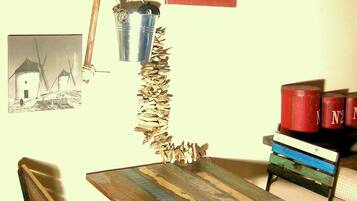 A rustic room with a wooden table and chairs, a windmill picture, a metal bucket, and a sign that reads "Dirty ovens Happy Kids".