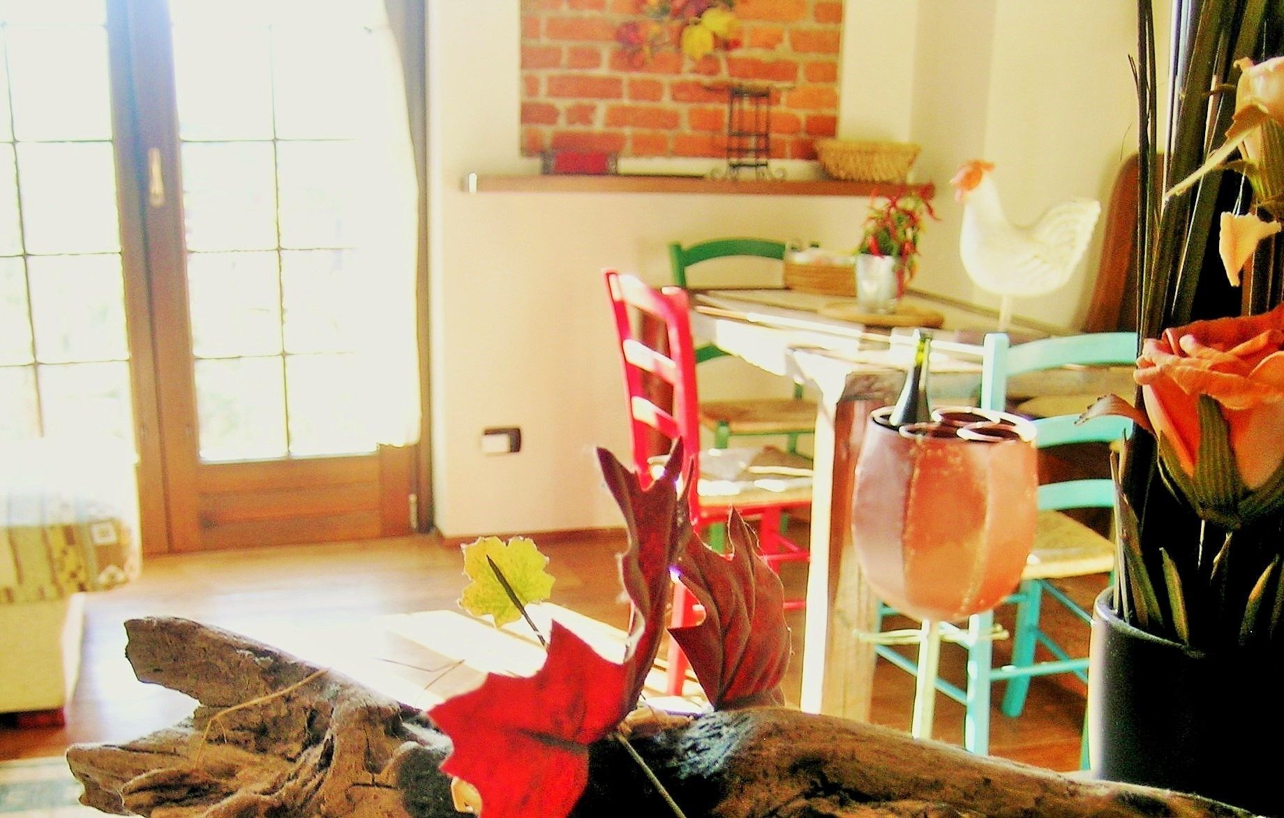 A dining area with a brick wall, a white chicken, and a table with chairs.