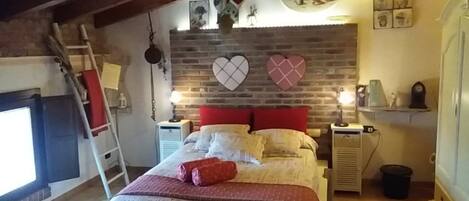 A cozy bedroom with a bed, a fireplace, and a brick wall.