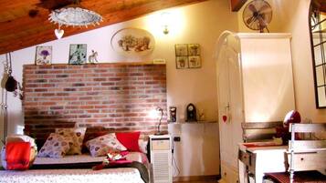 Ein gemütliches Zimmer mit Backsteinwand, einem Bett mit gemusterten Kissen, einem weißen Kleiderschrank und einem Schreibtisch mit Stuhl.