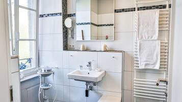 Ein modernes Badezimmer mit Waschbecken, Spiegel, Handtuchhalter und einem Fenster.