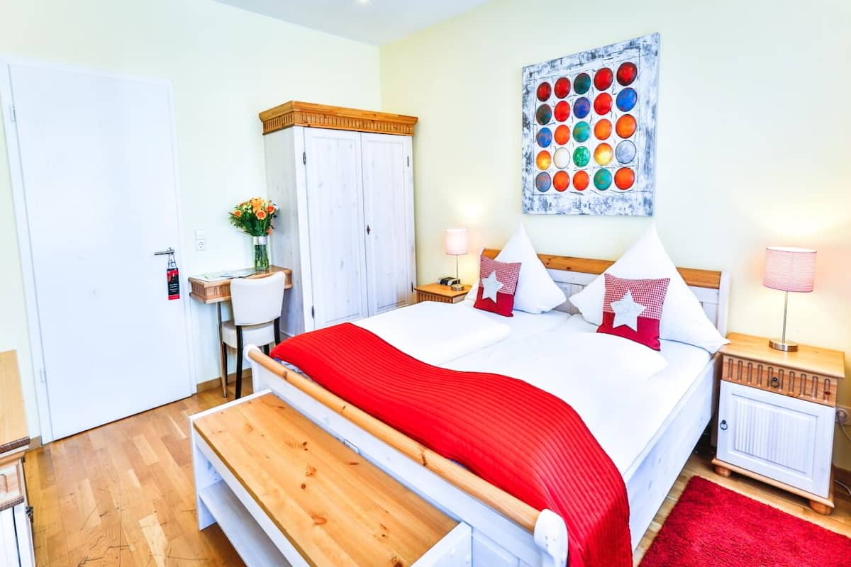 Un dormitorio con cama, mesitas de noche, armario, un banco y una obra de arte en la pared.