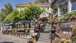 Une entrée d’hôtel charmante, avec une façade en pierre, une enseigne accueillante et un escalier menant à l’entrée principale.