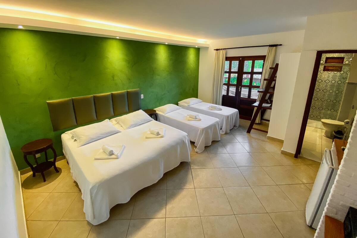 Habitación de hotel con dos camas individuales, una mesita, una silla y una ventana con cortinas.