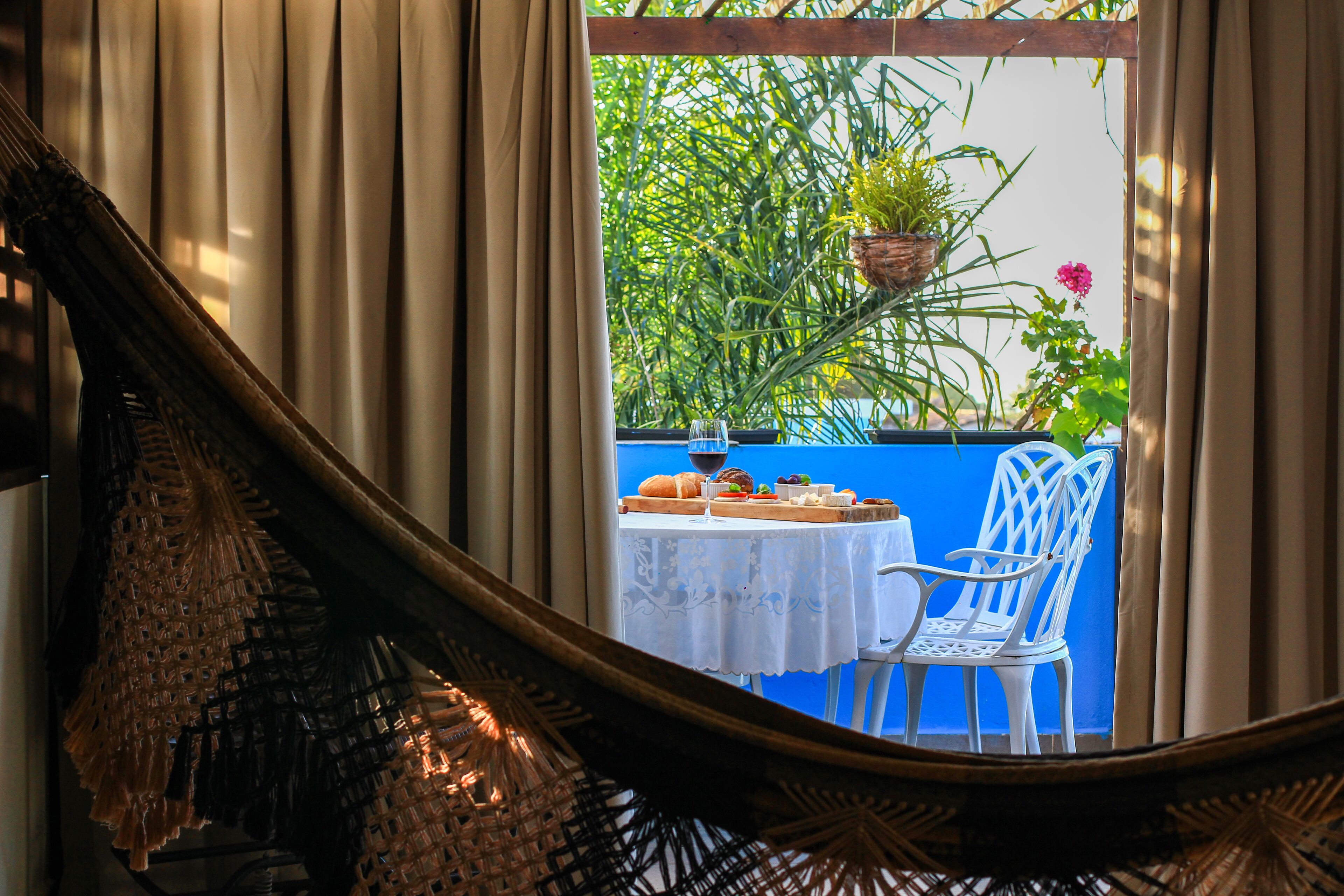 A wicker chair overlooking a table with a white tablecloth, a hanging plant, and a blue wall.