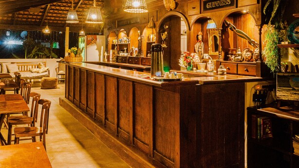 Un espace bar avec des meubles en bois, des luminaires suspendus et une enseigne Guinness.