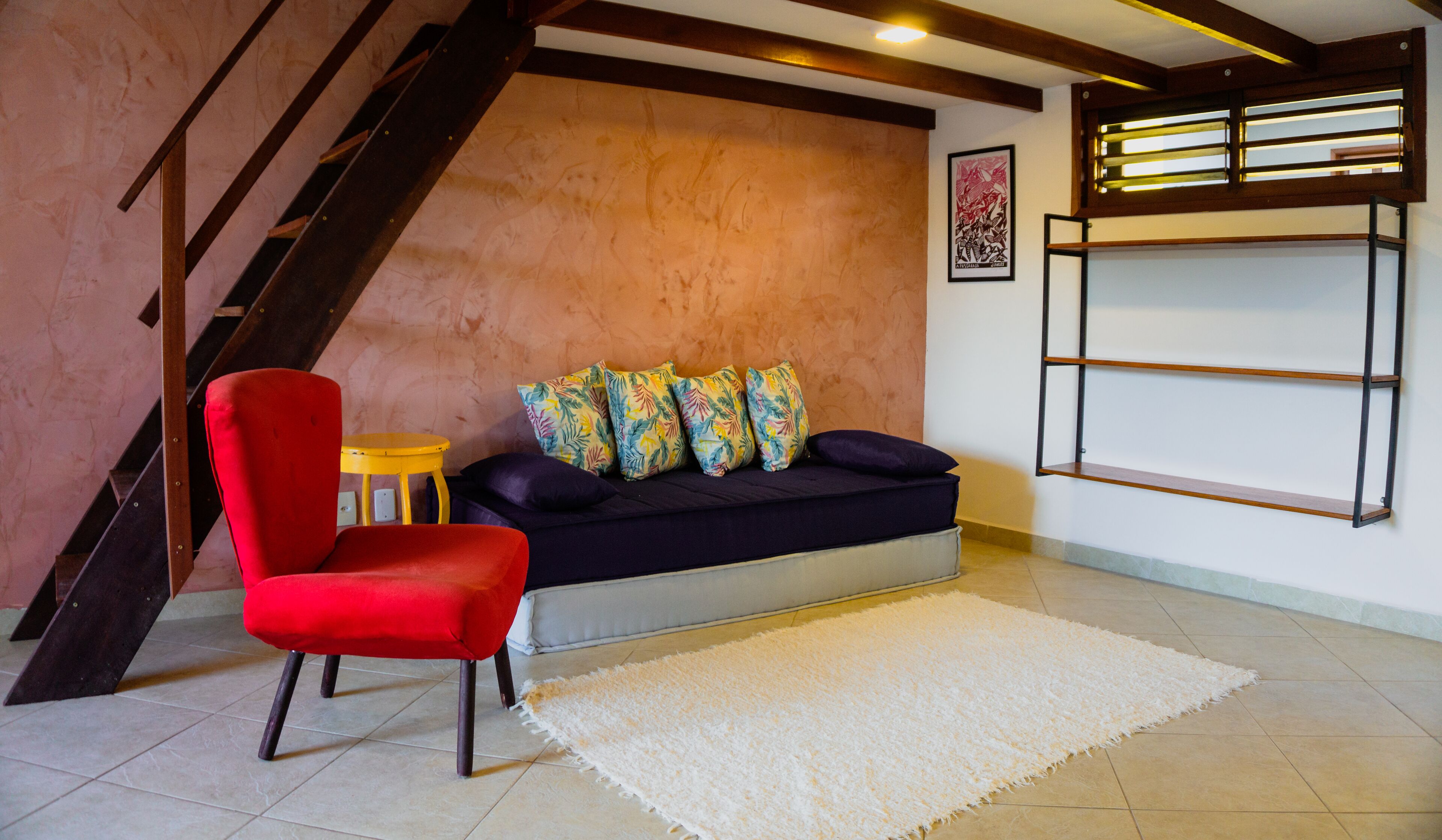 Un salon avec un canapé, un fauteuil rouge, une petite table et un tapis blanc.