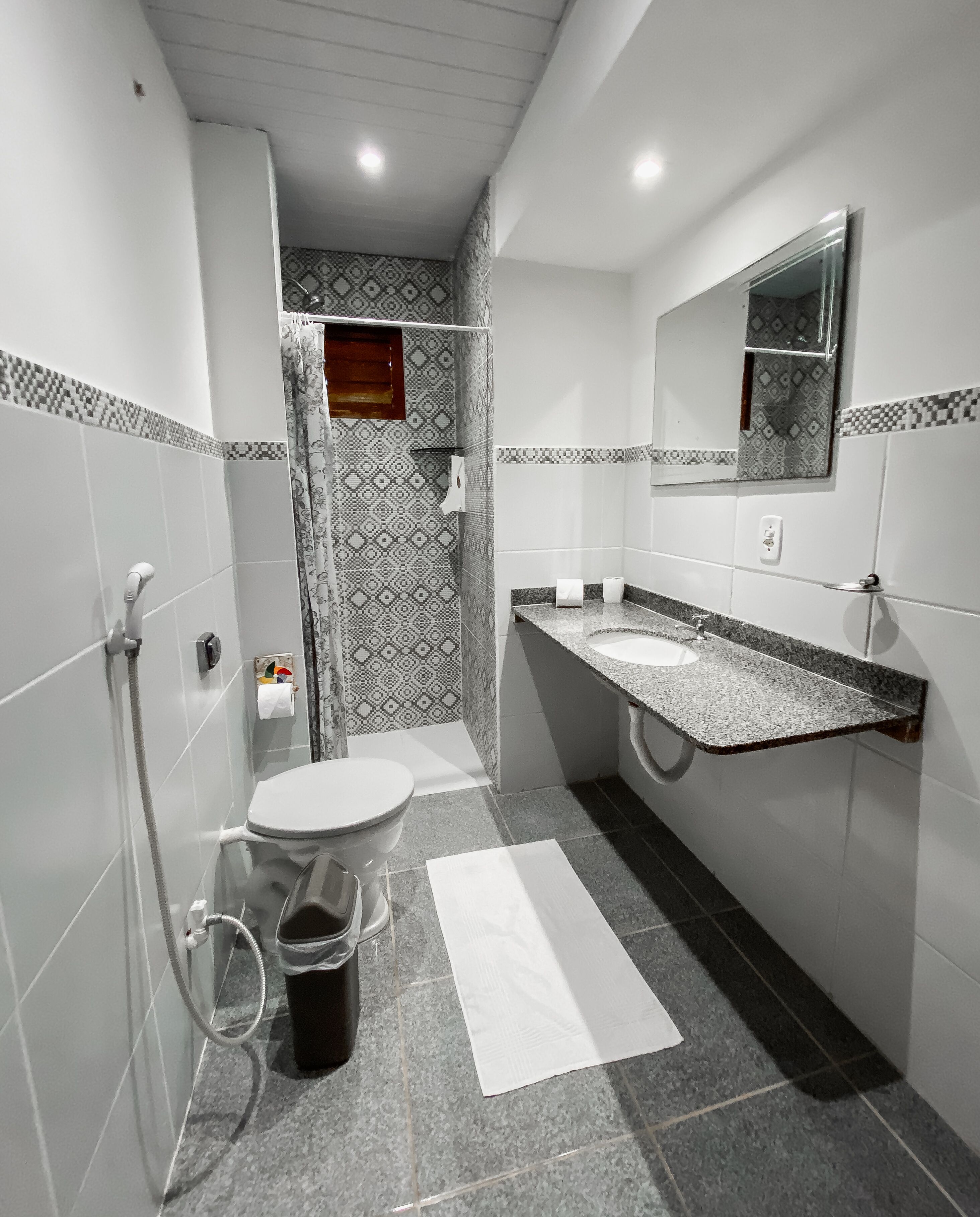 A bathroom with a toilet, sink, shower, and a mirror.