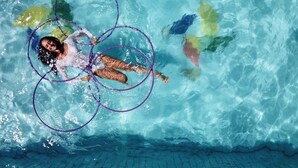 Une personne nage dans une piscine dont on peut voir les carreaux et le carrelage au fond.