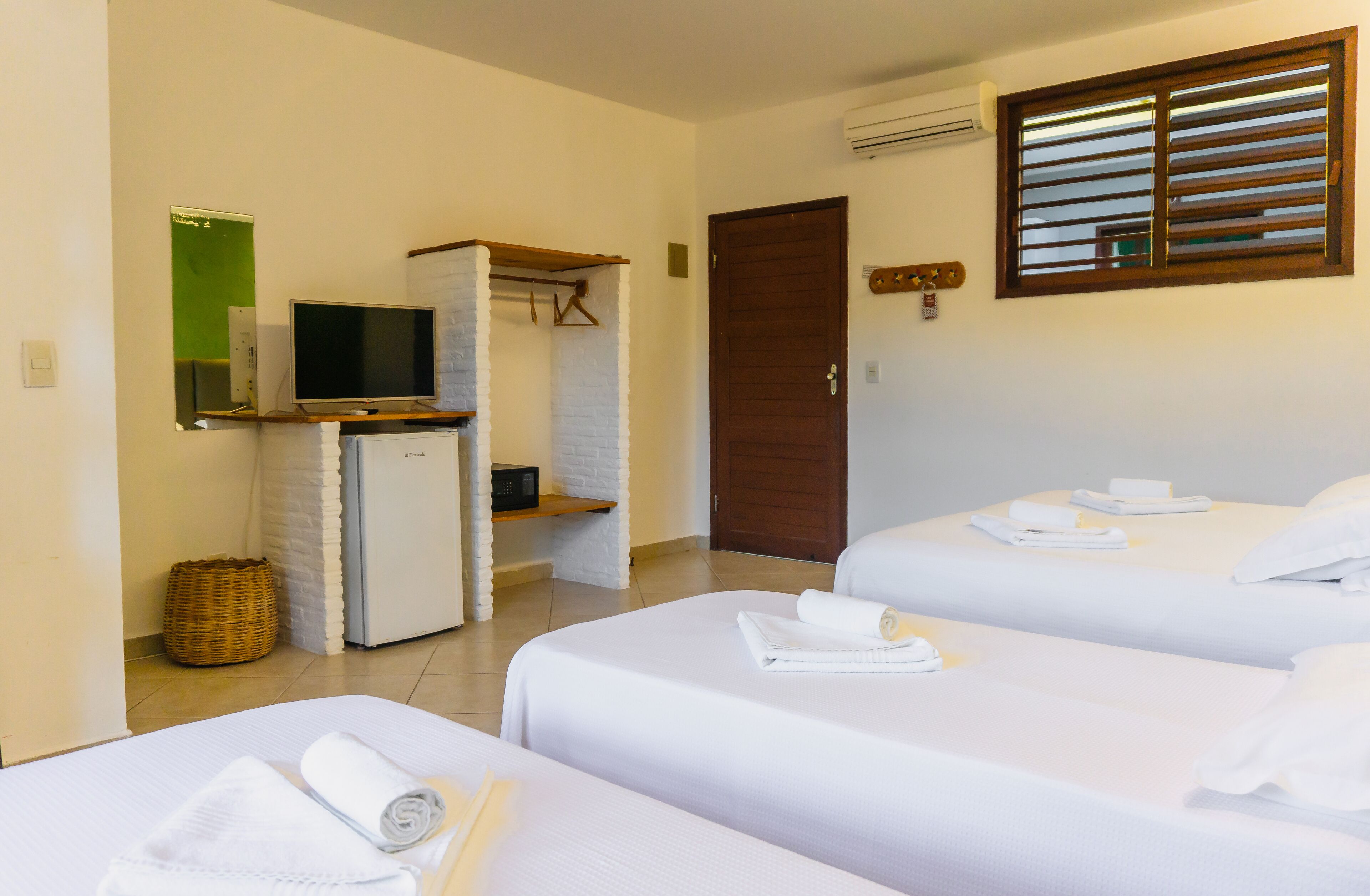 Une chambre d’hôtel avec deux lits, une télévision, une petite kitchenette et une porte.