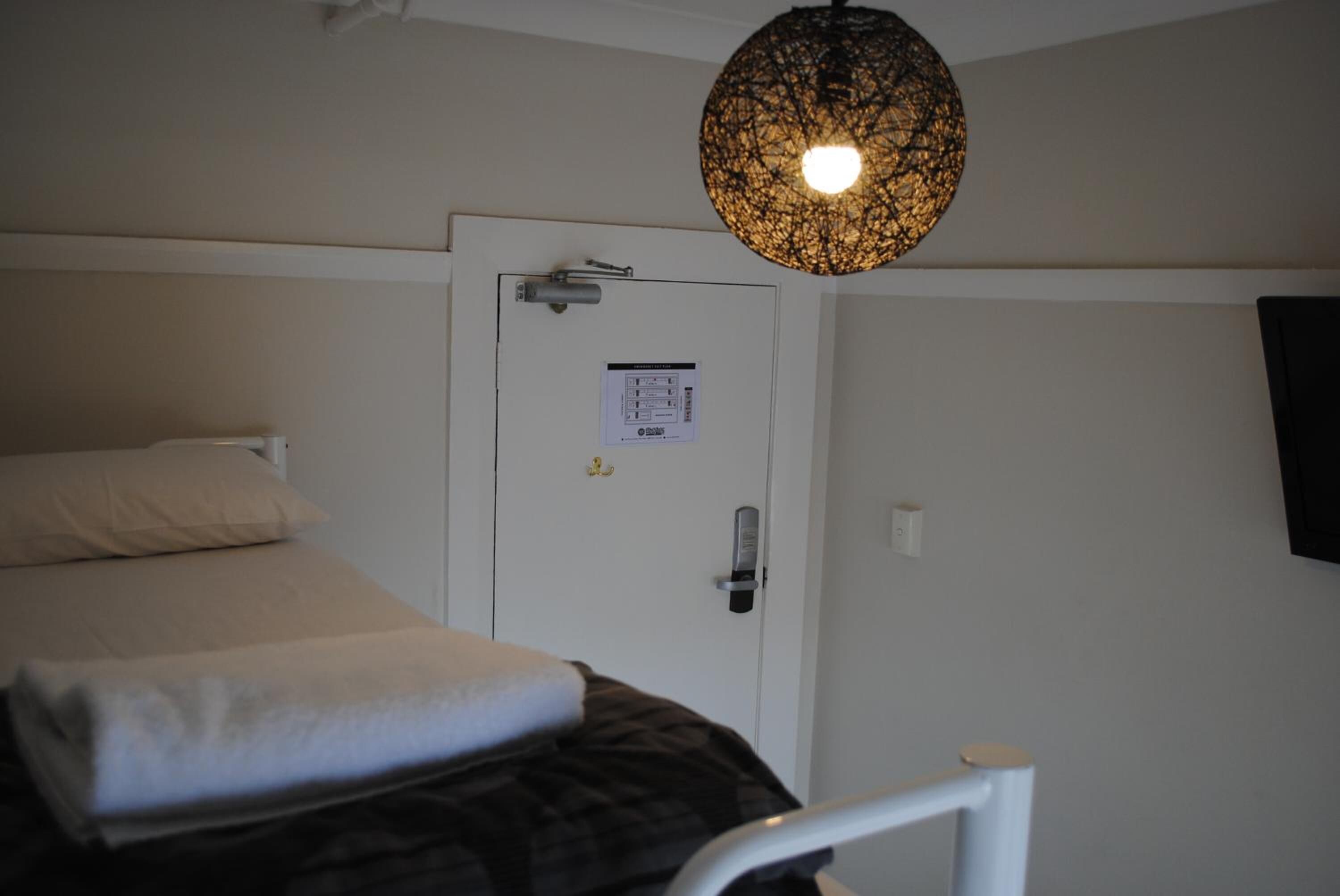 A room with a bed, a door with a lock, and a hanging light fixture.