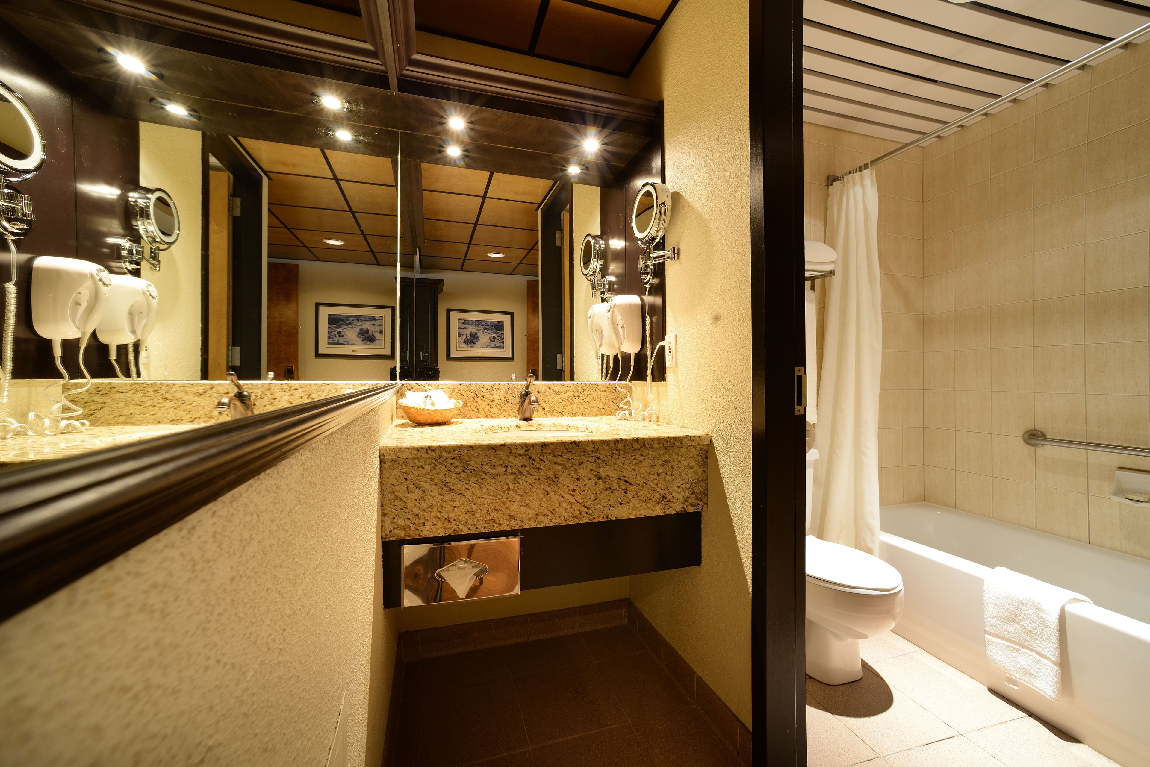 A bathroom with a granite countertop, a sink, a mirror, a toilet, and a bathtub.