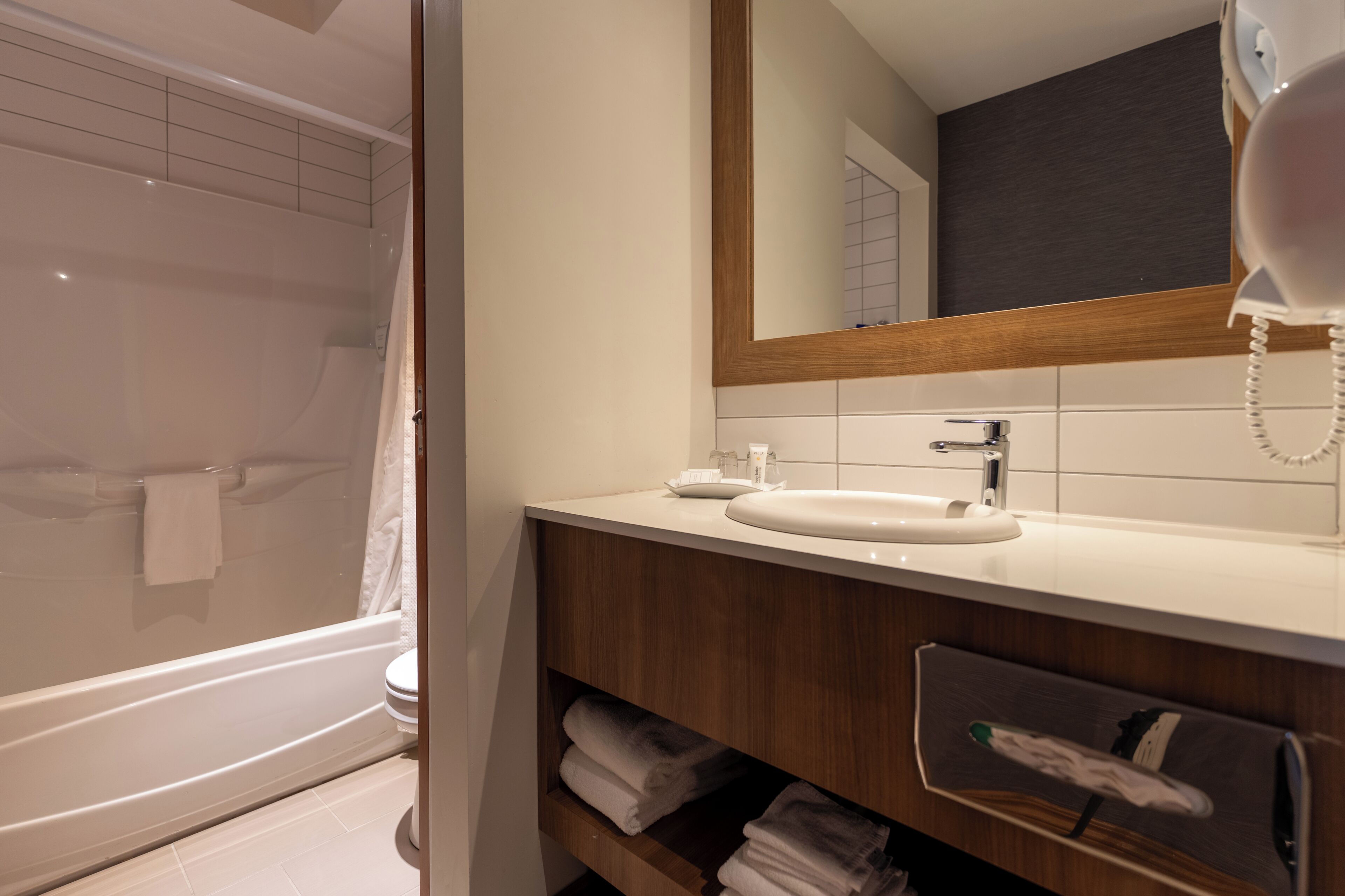 A modern bathroom with a bathtub, a sink, a mirror, and a telephone.