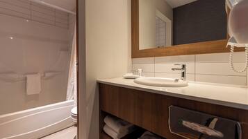 Un baño moderno con bañera, lavamanos, espejo y teléfono.