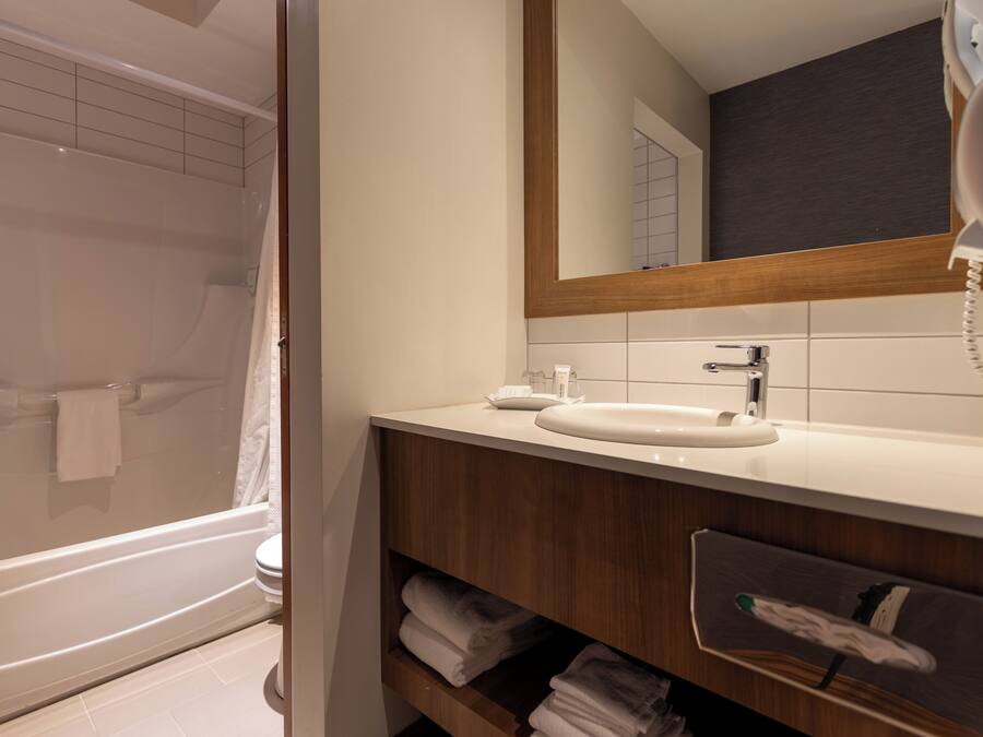 Un baño moderno con bañera, lavamanos, espejo y teléfono.