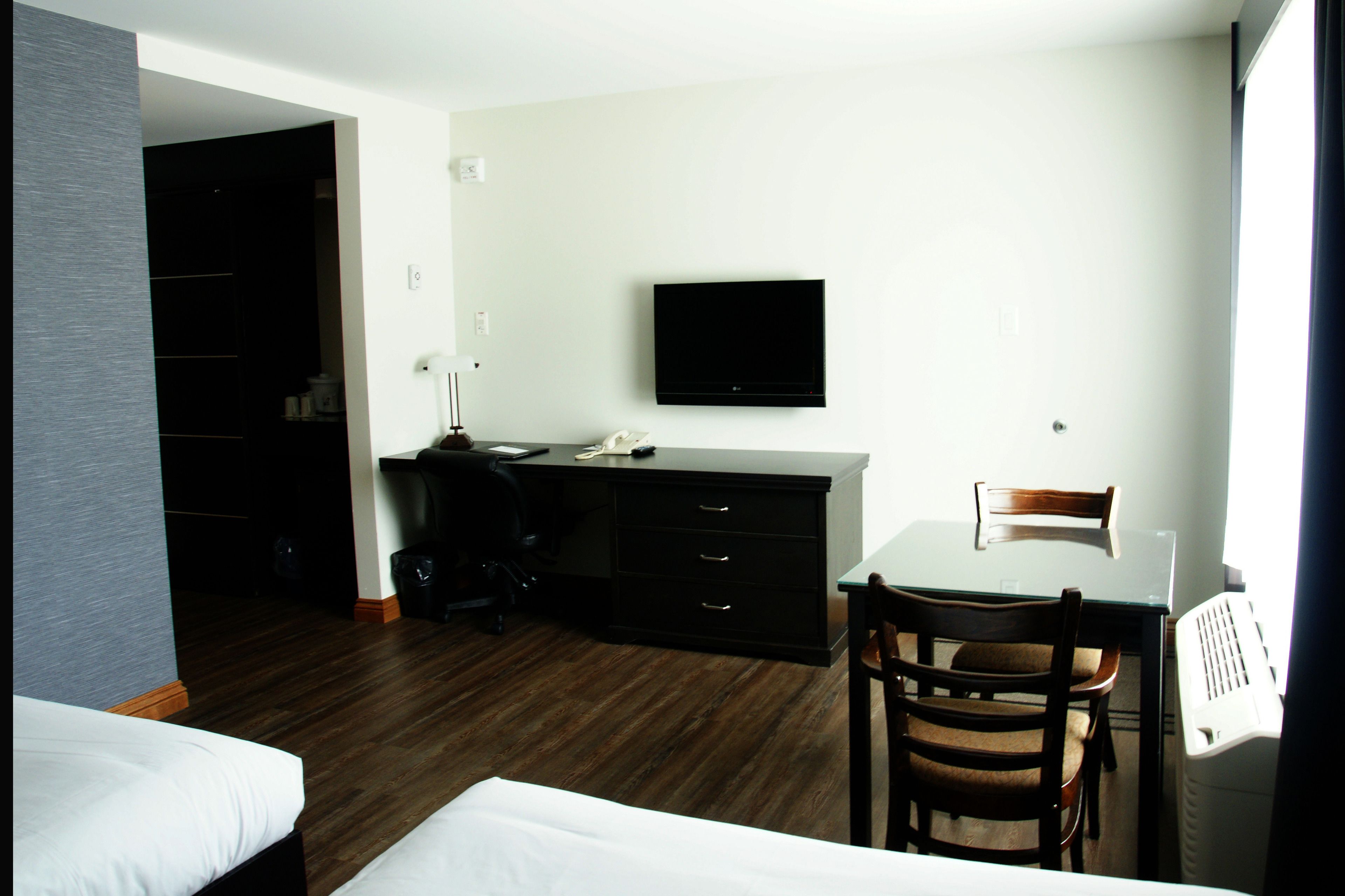 Een hotelkamer met een bed, bureau, stoel, televisie en kledingkast.