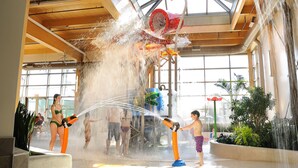 An indoor water play area with multiple water jets and a large decorative structure. - Le Montagnais (Saguenay)