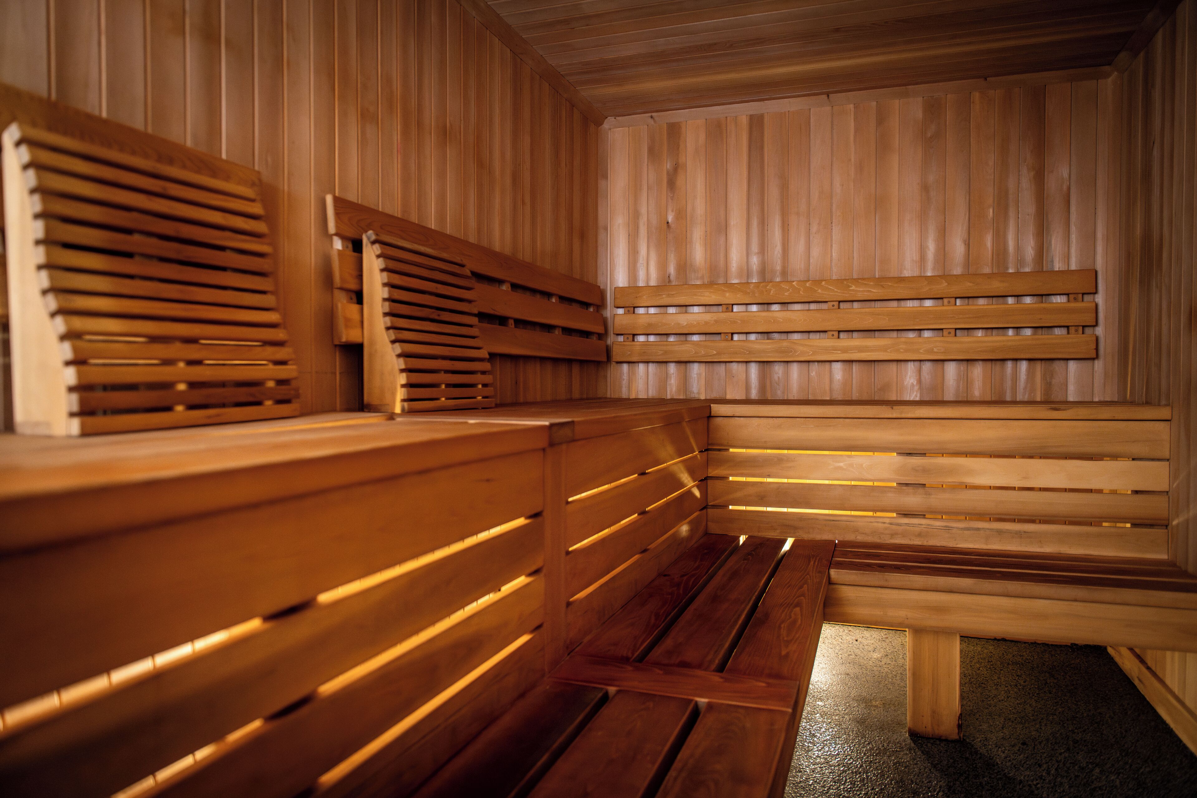 Una sauna con bancos de madera y respaldos de listones.