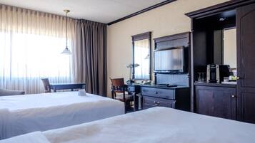 Een hotelkamer met twee bedden, een bureau, een stoel, een dressoir en een grote spiegel.